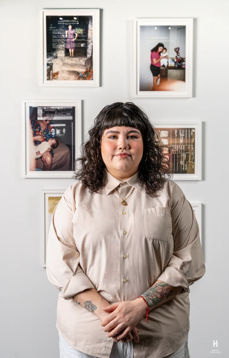 Adult with curly dark hair and bangs in a beige shirt and gold necklace, clasping hands to show floral forearm tattoos against six photos.